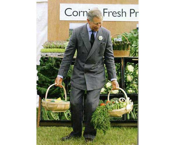 Prince Charles of England with a buttoned jacket carrying baskets of vegetables
